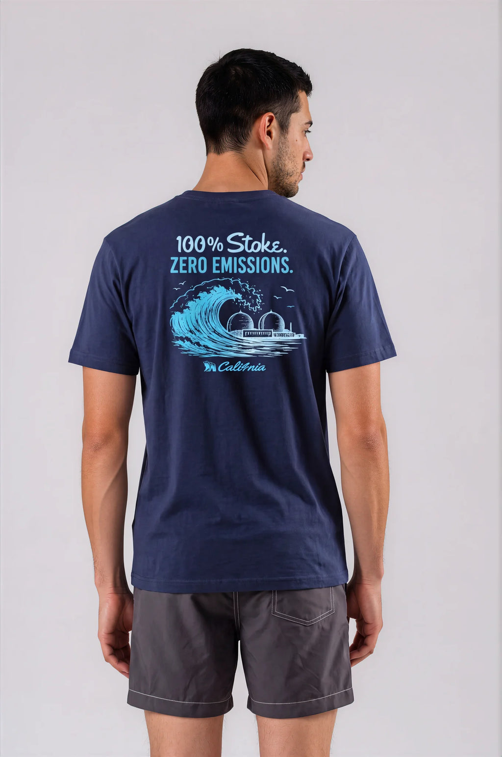 A man viewed from the back wearing a navy blue t-shirt with a large graphic on the back that reads '100% Stoke. ZERO EMISSIONS.